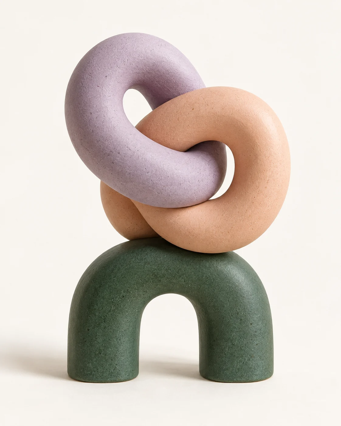 Interlocking lilac and peach sculptures balanced on a forest-green arch